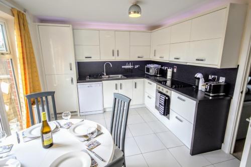 a kitchen with white cabinets and a table with a bottle of wine at Martello Sunrise - Luxury 3-bedroom Seaview Beach House in Felixstowe