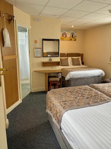 a hotel room with two beds and a desk at Clifton Court Hotel in Blackpool