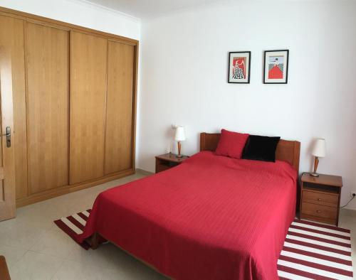 a bedroom with a bed with a red bedspread and wooden cabinets at Albufeira Bicos Beach Apartment in Albufeira