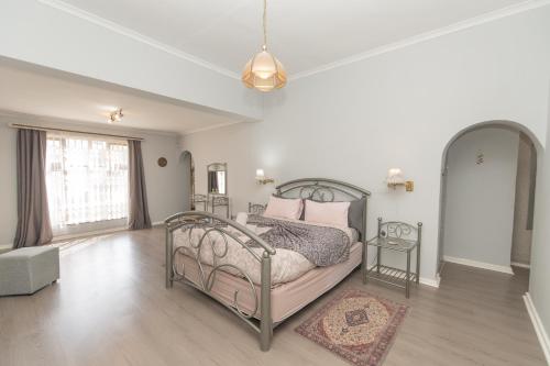 a white bedroom with a bed with pink pillows at Paradise On Water Road in Gqeberha