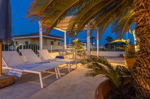 a patio with chairs and a table and a palm tree at Terrazza delle Anfore in Capilungo