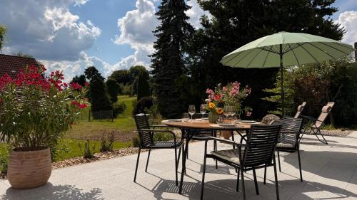Una mesa con sillas y una sombrilla en un jardín. en Helles Ferienhaus mit 2 Terrassen, en Uttenweiler