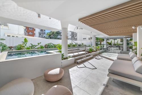 an apartment patio with a pool and tables and chairs at The Cotton Tree - Luxury 3BR Apt Pool Gym BBQ Free Prkg 1min to Beach in Maroochydore