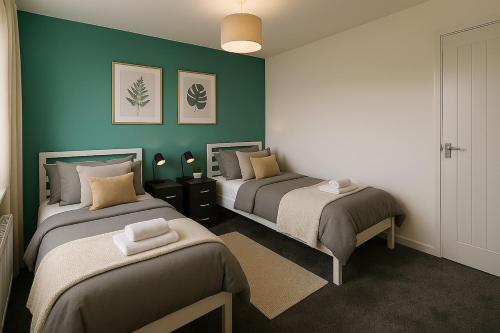 two beds in a room with green walls at Near West Cumbria Hospital in Whitehaven