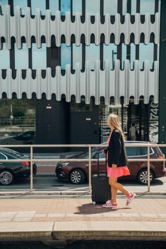 a woman walking down a sidewalk with a suitcase at The Zipper Hotel und Apartments in Düsseldorf