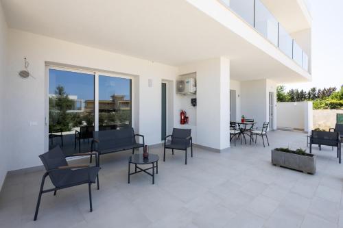 a large patio with chairs and tables and windows at Dara Holiday Apartments in Marsala