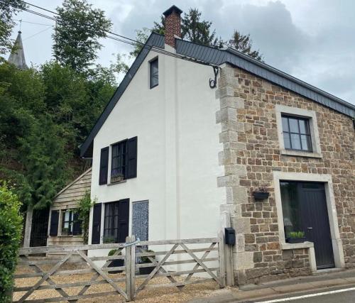 an old brick and white house with a fence at Au coeur de la Vallée in Érezée