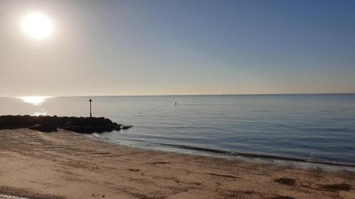 a beach with the sun rising over the water at Martello Sunrise - Luxury 3-bedroom Seaview Beach House in Felixstowe