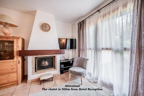 a living room with a fireplace and a chair and a clock at Eden Hotel, Apartments and Chalet Chamonix Les Praz in Chamonix-Mont-Blanc
