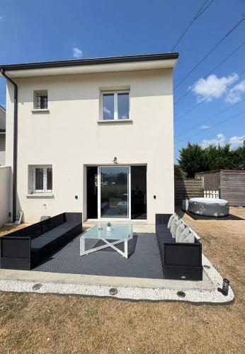 a white house with a couch and a table at Maison entiere jacuzzi reception ouverte 7 7j et 24 24h in Ambarès-et-Lagrave