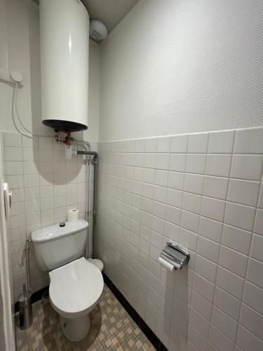 a bathroom with a toilet and a white tiled wall at Studio Manuia Climatisé au centre ville in Digoin