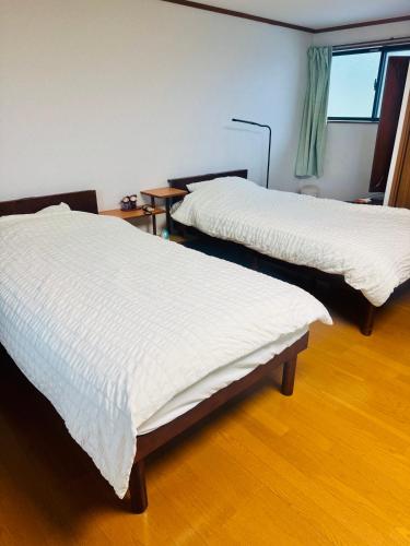 a room with two beds with white sheets on them at Remote Retreat Shikawa リモートリモート志川 in Saijo