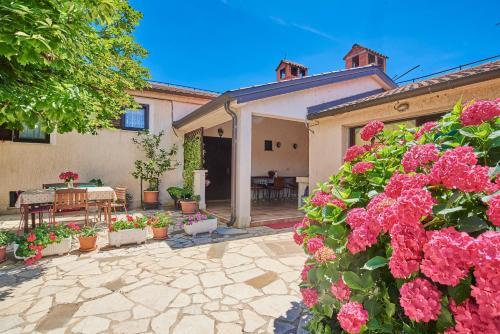 a house with a patio with flowers and a table at B&B Carmela in Umag