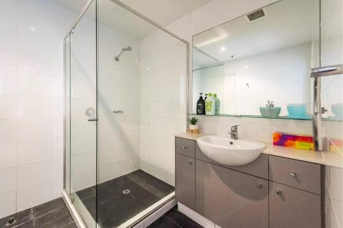 a bathroom with a sink and a glass shower at Barrack Street City Pad 2br 2 Bth in Perth