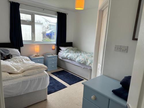 a small bedroom with two beds and a window at Bungalow with stunning views over Widemouth Bay in Widemouth Bay