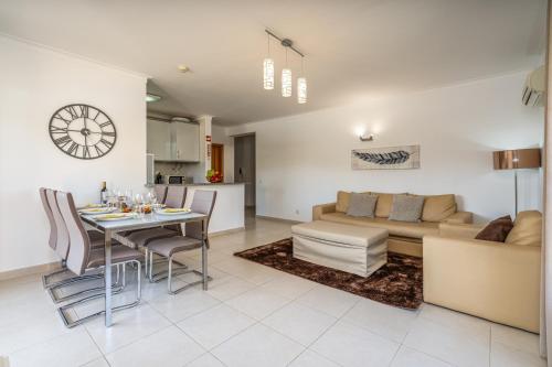 a living room with a couch and a table with chairs at Spacious & Sunny Apartment with Pool by HostWise in Portimão
