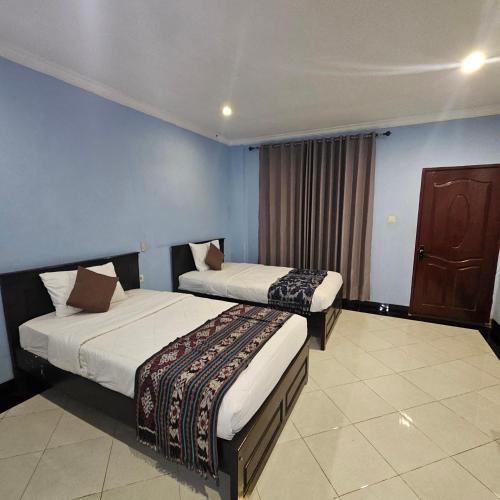 two beds in a room with blue walls at Ridho Malik Hotel in Bumbang