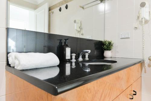 a black bathroom counter with a sink and a mirror at Harbour Home 2BR Apt - Family Friendly Gem in Sydney
