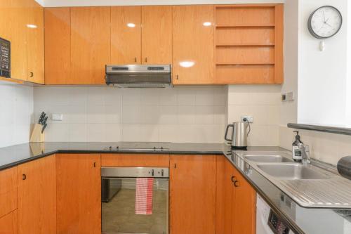 a kitchen with wooden cabinets and a sink at Harbour Home 2BR Apt - Family Friendly Gem in Sydney