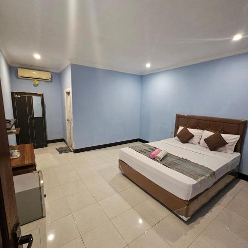 a bedroom with a bed and a blue wall at Ridho Malik Hotel in Bumbang