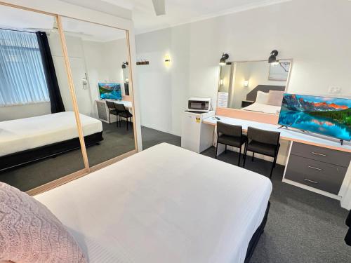 a room with two beds and a desk with a mirror at Golden Sands Motor Inn in Forster