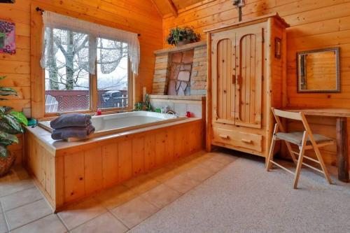 a bathroom with a tub and a table and a window at Snuggle Bug By Beyond Expectations Views Pool in Gatlinburg
