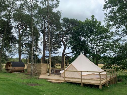 a tent and a wooden platform in a field at North Lodge Glamping in Carnwath