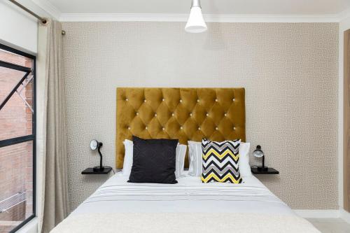 a bedroom with a large bed with a yellow headboard at #AlimamaSpaces Manson's Fynbos Villa in Cape Town