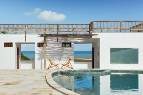 a house with a swimming pool and two chairs at Pousada Villa Tibá in Jericoacoara