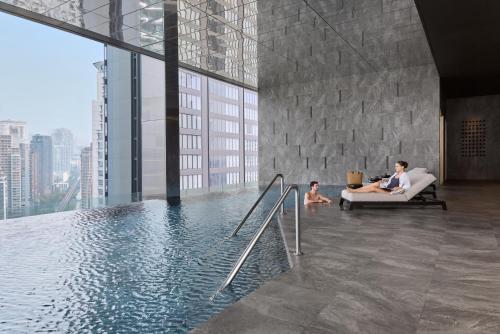 a woman and child sitting on a couch next to a pool at InterContinental Bangkok Sukhumvit by IHG in Bangkok