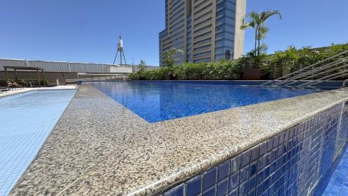 a swimming pool with a blue tiled wall next to a building at Apt de Luxo IV no Shopping DF Plaza - Aguas Claras in Brasilia