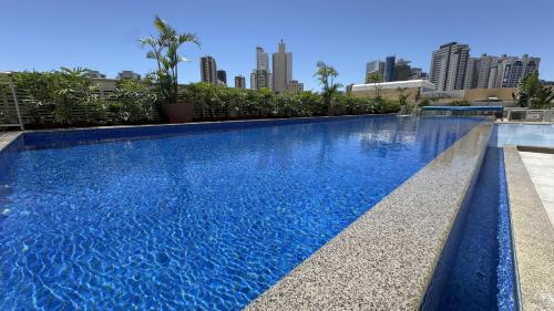a blue swimming pool with a city skyline in the background at Apt de Luxo IV no Shopping DF Plaza - Aguas Claras in Brasilia