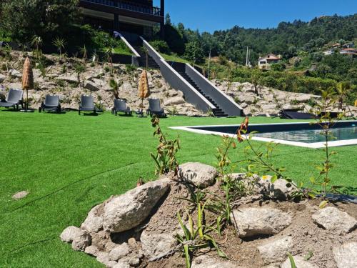a green lawn with chairs and a pool with umbrellas at Abadia House - Geres in Geres