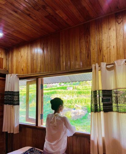 a woman looking out of a window in a room at Táo Tày House in Sa Pa