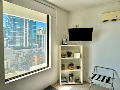 a room with a window with a tv and a chair at 806 Deluxe Delight Concert Hall Studio in Perth