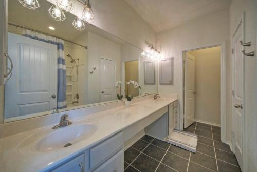 a bathroom with a sink and a large mirror at Sunny Delight Of Pville - Where Days Are Bright in Pflugerville