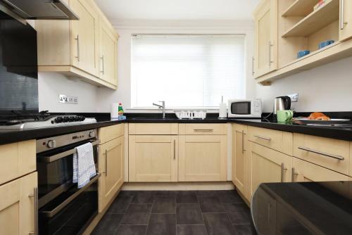 a kitchen with wooden cabinets and black counter tops at Ideal Bath House by St James’s Park in Bath
