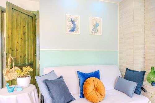 a living room with a white couch and blue pillows at Villino Le Pavoncelle in Torre delle Stelle