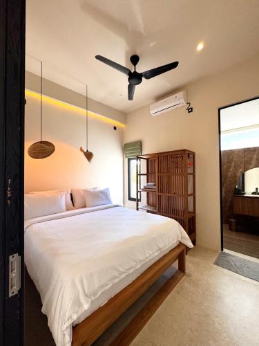 a bedroom with a large bed with a ceiling fan at Casa Narrow Villa in Nembrala