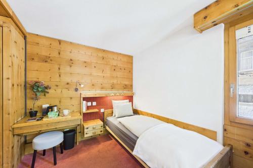 a bedroom with a bed and a desk and a chair at Cozy Single Suite in the Heart of Saas-Fee in Saas-Fee