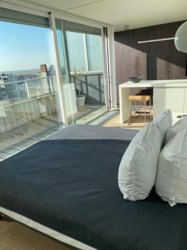 a bedroom with a large bed and a balcony at Penthouse Sea-Loft Blankenberge, uniek zeezicht, Luxeloft met 40m2 terras! in Blankenberge