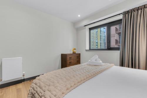 a white bedroom with a bed and a window at Chic Luna Apartments near Wembley Park by MySquare in London