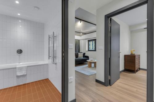 a bathroom with a walk in shower next to a living room at Chic Luna Apartments near Wembley Park by MySquare in London