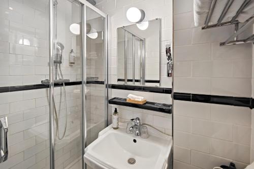 a white bathroom with a sink and a shower at Hôtel de France, un hôtel AMMI in Nice