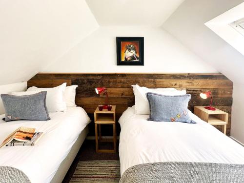 two twin beds in a attic room with two tables at The Barn at Orford Lodge by The Suffolk Cottage Collection in Orford