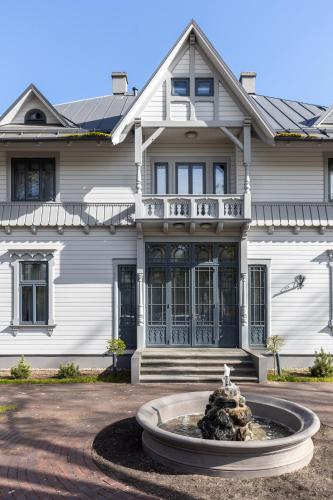 a large white house with a fountain in front of it at Roze Peldu Residence in Liepāja
