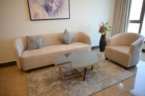 a living room with a couch and a table and two chairs at Best Western Plus Mahboula in Kuwait