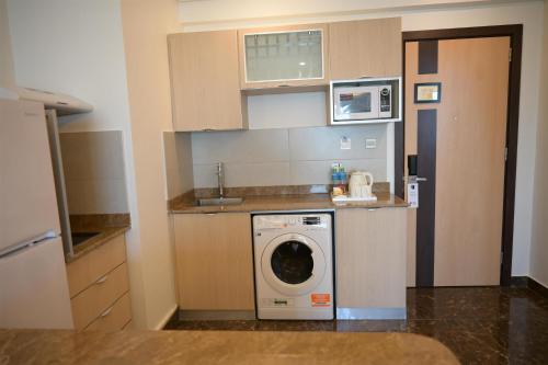 a kitchen with a washing machine and a microwave at Best Western Plus Mahboula in Kuwait