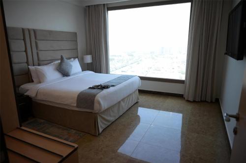 a hotel room with a bed with a large window at Best Western Plus Mahboula in Kuwait