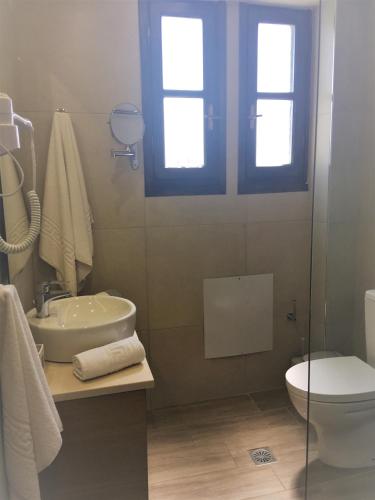 a bathroom with a sink and a toilet and a window at Georges Estates Hotel in Stoupa